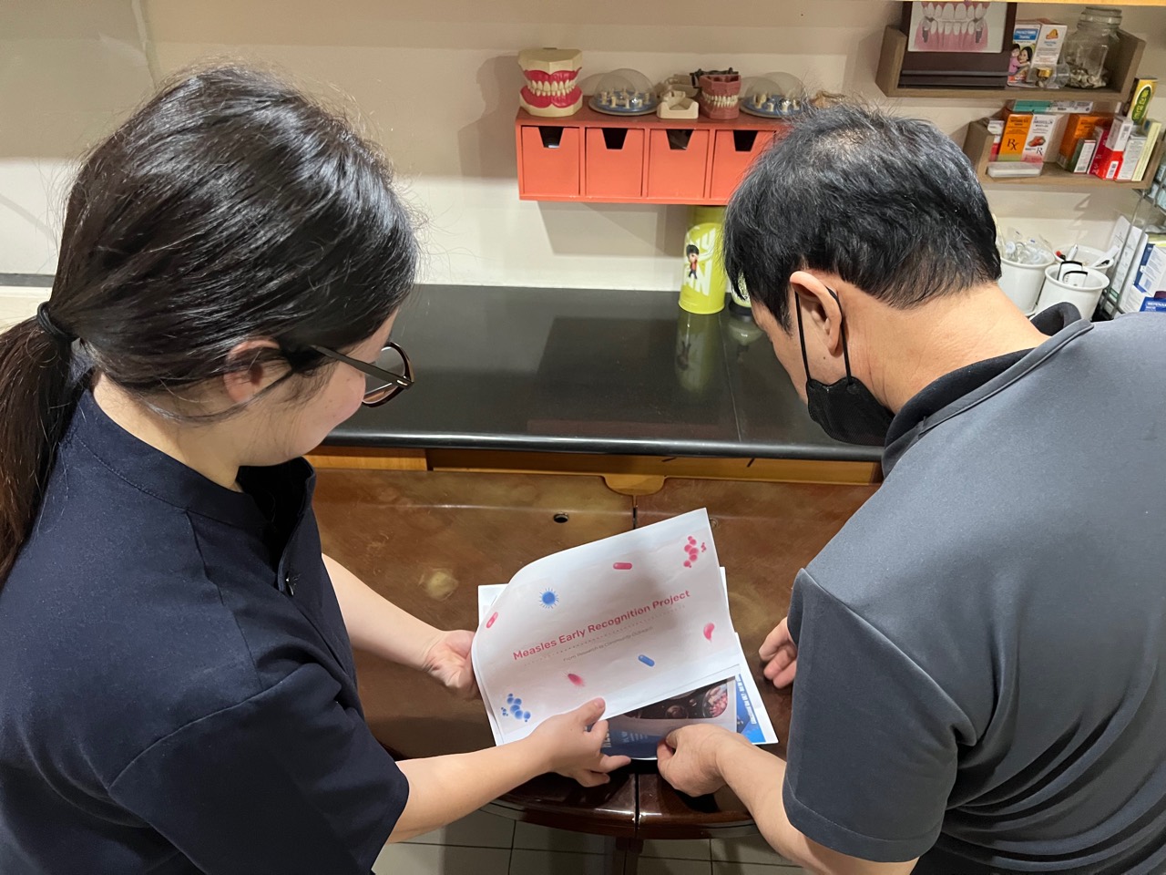 Minji reviewing printed measles early-recognition materials one-to-one